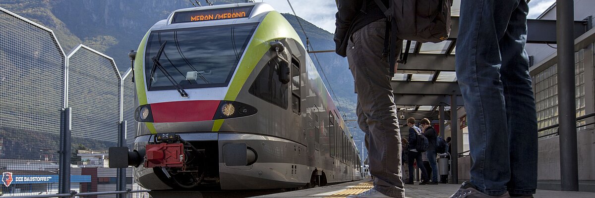 People and students waiting for the train at the station. The train is approaching